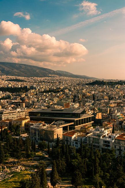 Scenic aerial view of Athens featuring the Acropolis Museum and cityscape under a cloudy sky.