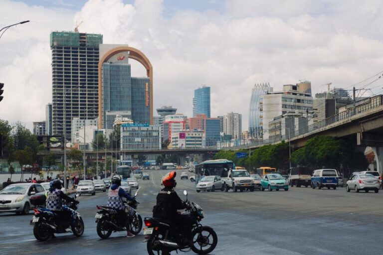 Bikers and cars bustling in Addis Ababa's cityscape with iconic buildings and clear skies.
