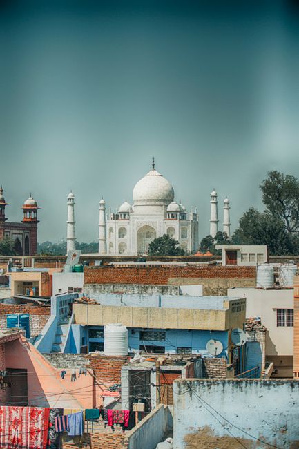 Majestic view of the Taj Mahal with foreground of Agra's vibrant rooftops, capturing urban and historical contrast.