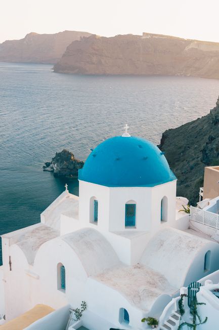 Stunning view of a blue-domed church in Santorini with breathtaking coastal scenery.