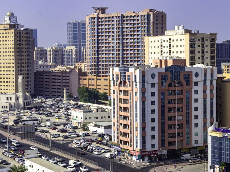 Aerial view of Ajman's urban skyline featuring highrise apartment buildings and busy streets.