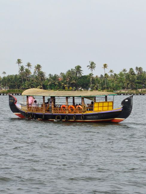 Scenic view of a traditional Kerala houseboat cruising on Alappuzha backwaters, surrounded by lush greenery.