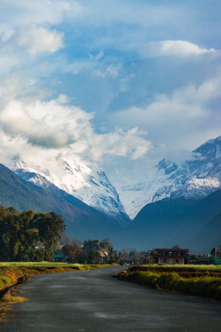 Breathtaking view of snow-capped mountains and a winding road beneath a cloudy sky, ideal for travel and nature themes.