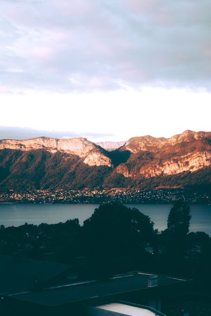 Golden sunrise over Lake Annecy with majestic mountains, perfect for nature and travel enthusiasts.