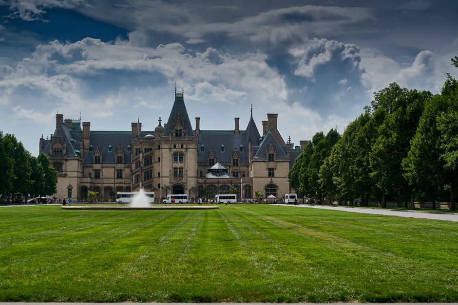 Stunning view of Biltmore Estate in Asheville with vibrant gardens and clear sky, showcasing architectural grandeur.
