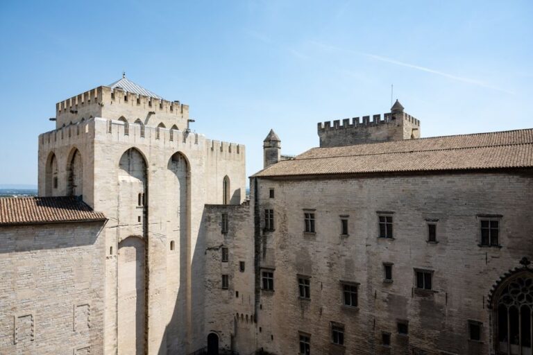 View of the historic Palace of the Popes in Avignon, showcasing Gothic architecture under a clear blue sky.