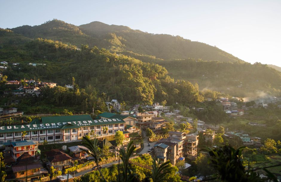 Aerial view of the Immaculate Conception School amidst the mountains of Banaue, Philippines at sunrise.