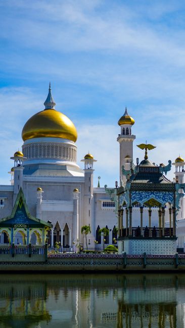 Majestic view of Sultan Omar Ali Saifuddien Mosque with reflective water foreground and blue skies.