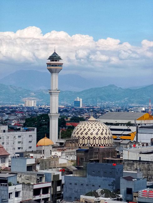 Scenic view of Bandung cityscape featuring the iconic Lalakon tower against mountainous backdrop.
