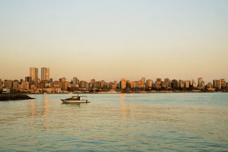 A serene view of the Beirut skyline with a boat on calm waters during sunset.