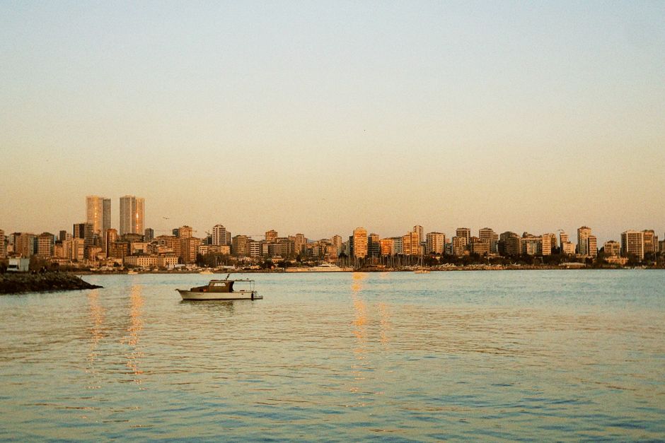 A serene view of the Beirut skyline with a boat on calm waters during sunset.