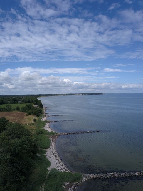 Aerial photo of the Danish coastline with lush greenery and clear blue seas on a bright day.