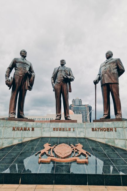 Statues of historical leaders in Gaborone, Botswana, against a cloudy sky.
