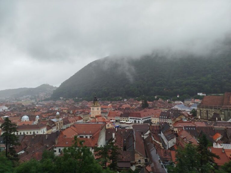 Aerial view of Brașov, Romania, showcasing historic architecture and Mount Tâmpa under a cloudy sky.