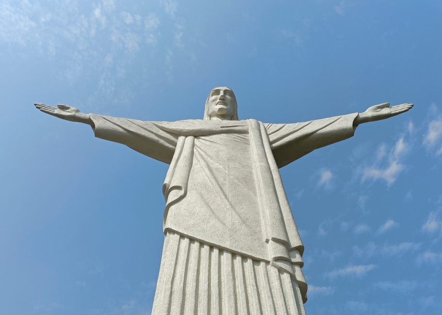 Close-up view of the iconic Christ the Redeemer statue against a blue sky in Rio de Janeiro.