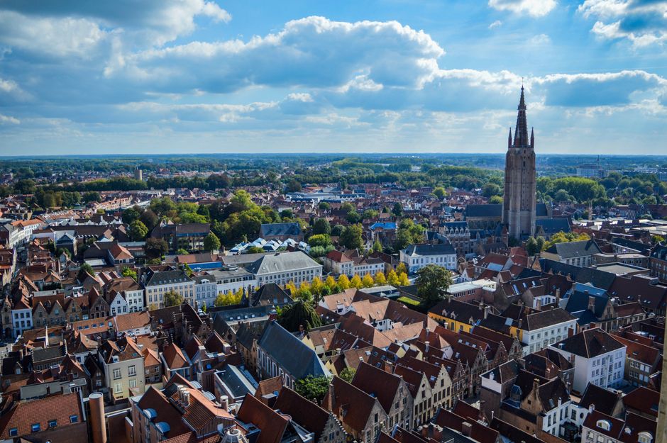 Aerial shot of Bruges cityscape showcasing the historic Belfry under a partly cloudy sky.