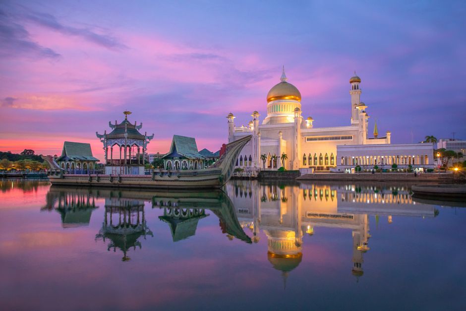 Stunning view of Sultan Omar Ali Saifuddin Mosque reflecting in the water at sunset in Brunei.