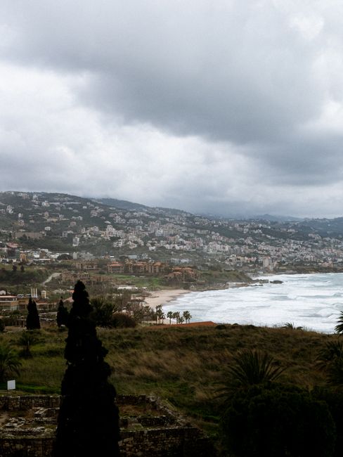 Overcast day in Lebanese coastal town with hills and sea view.