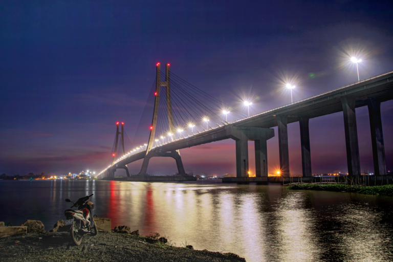 A stunning view of the illuminated Can Tho Bridge reflecting in the river at night.