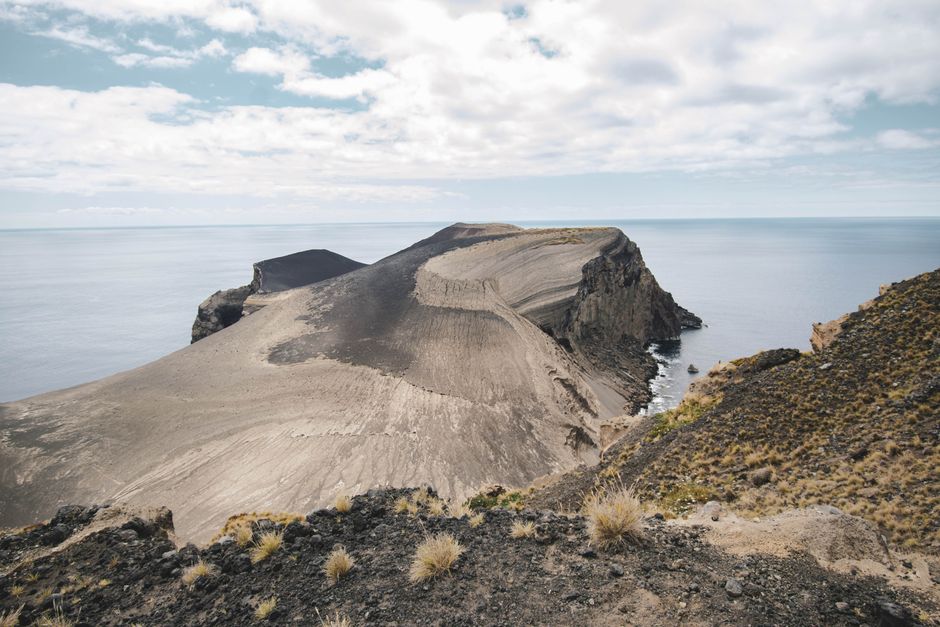 Explore this breathtaking coastal cliff formed by ancient volcanic activity beside a serene sea.