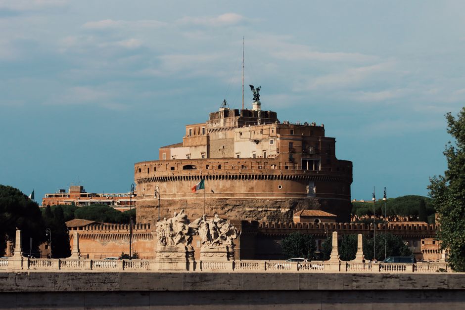 View of Castel Sant'Angelo in Rome with statues and vibrant summer sky.