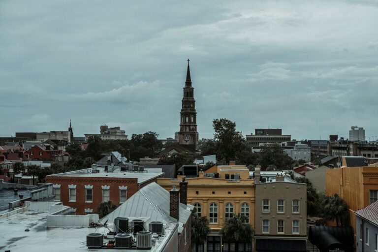 A picturesque view of Charleston, SC, featuring a historic church tower amidst vibrant buildings.
