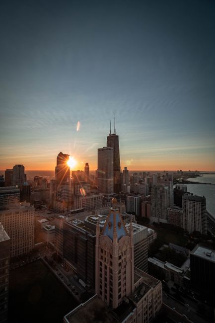 Captivating view of Chicago's skyline with sunburst over skyscrapers, Lake Michigan visible.