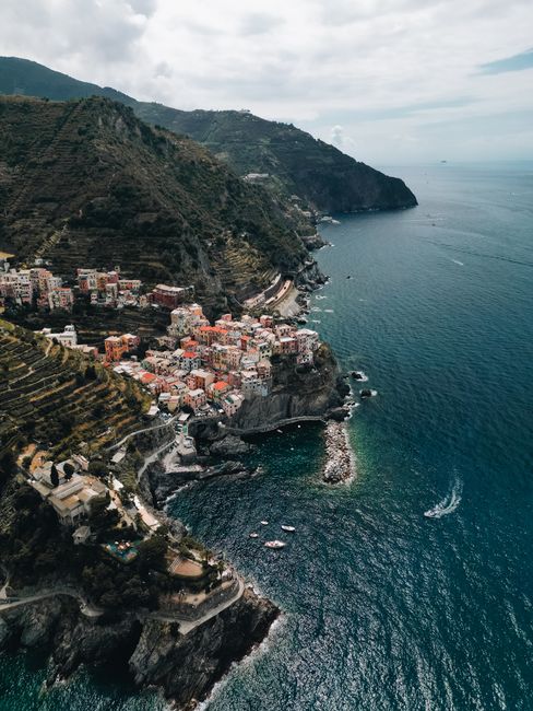 Stunning aerial view of Manarola, capturing the colorful cliffside village and azure sea of Liguria, Italy.