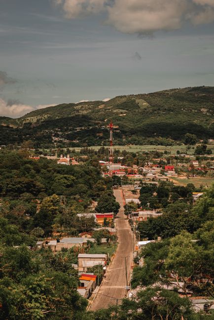 Explore a picturesque town nestled in a lush valley with green hills in the backdrop, captured in a vibrant summer setting.