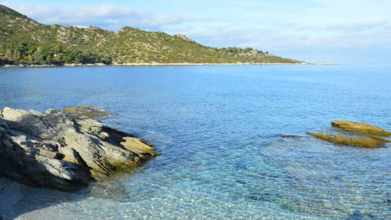 Captivating coastal landscape of Patrimonio, Corsica with clear blue waters and rocky shorelines.