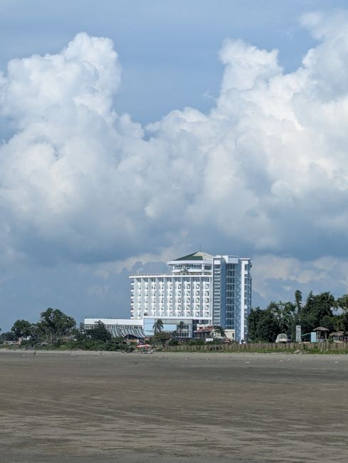 A tall hotel building by the beach with a dramatic cloudy sky in Cox's Bazar, Bangladesh.