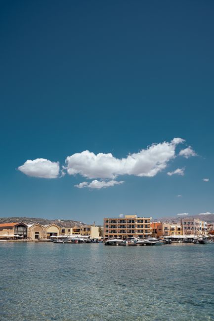 Peaceful view of Heraklion harbor with clear skies and calm water, perfect for summer travel.