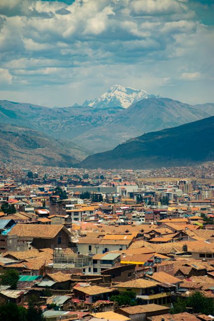 A vibrant cityscape of Cusco, Peru, framed by majestic mountain ranges.