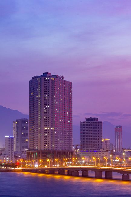 Beautiful Da Nang skyline illuminated at dusk with vibrant city lights and purple skies.