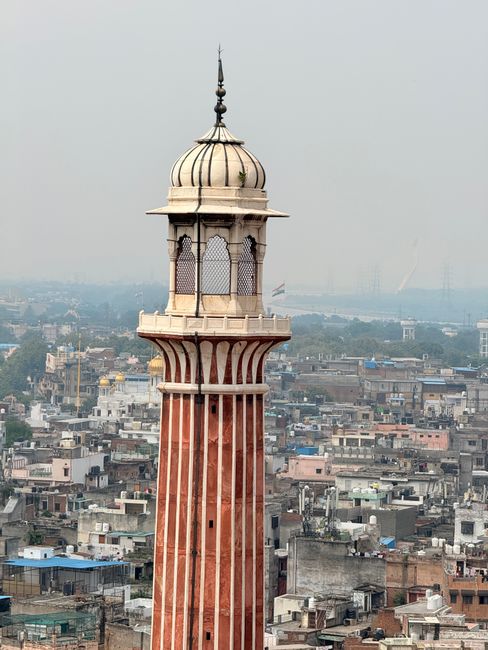 Majestic minaret rises above Delhi's vibrant urban landscape, showcasing architectural beauty.