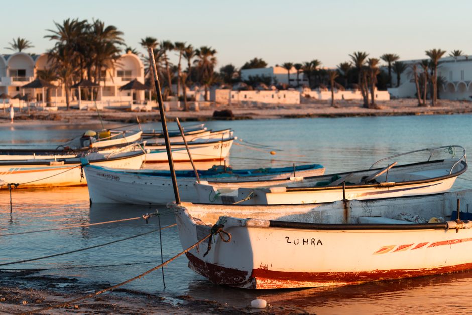 Small fishing boats anchored at sunset on the Tunisian coast, capturing a tranquil seaside scene.