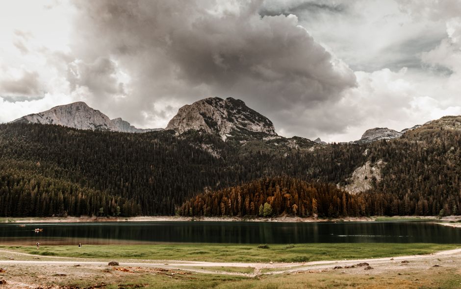Serene mountain landscape of Black Lake and forests in Montenegro under dramatic clouds.