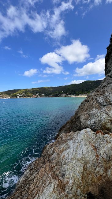 A stunning view of the rocky coastline by the clear blue waters on a sunny day.