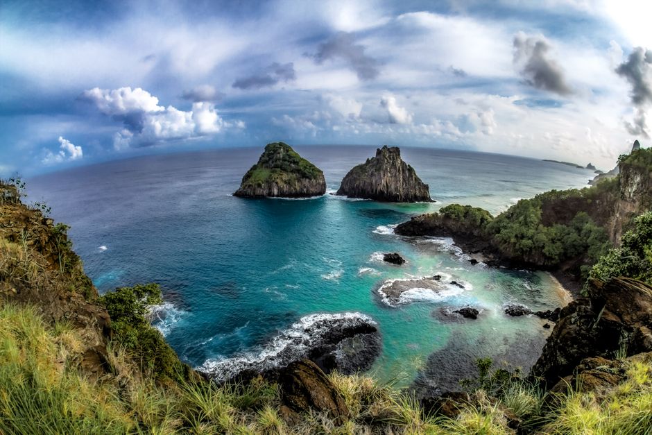 Breathtaking coastal scene at Fernando de Noronha with rocks and deep blue ocean under cloudy sky.