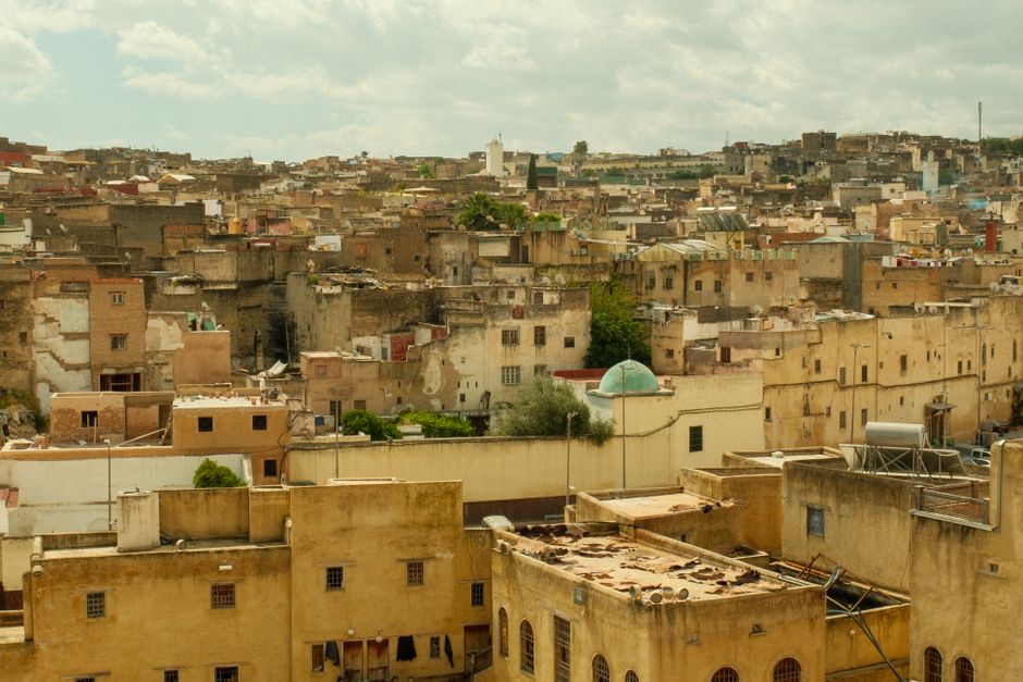 Aerial view of Fes city showcasing historic architecture and rustic rooftops under a cloudy sky.