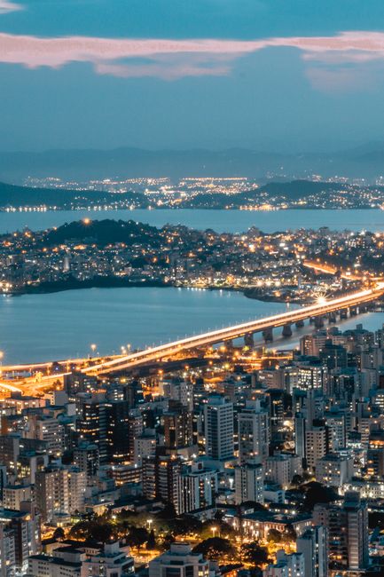 Stunning aerial view of Florianópolis cityscape with illuminated bridge and coastline at twilight.