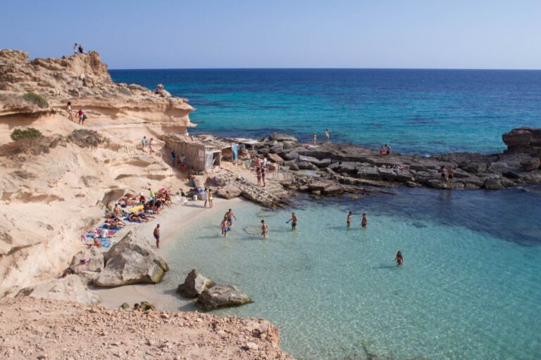 Stunning coastline photo capturing beachgoers at a rocky cove in Illes Balears, Spain.