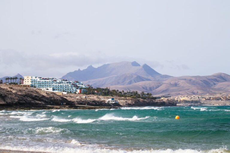 Scenic view of Fuerteventura coastline with waves and mountains in the background.