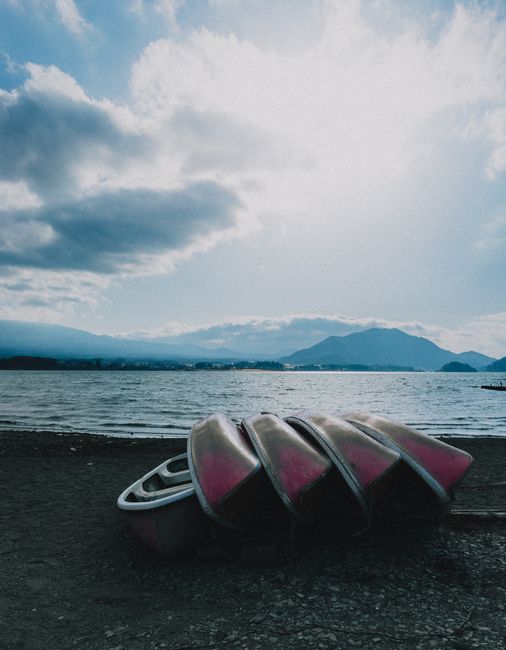 Dramatic view of Lake Kawaguchi with stacked canoes and Mount Fuji in the background.