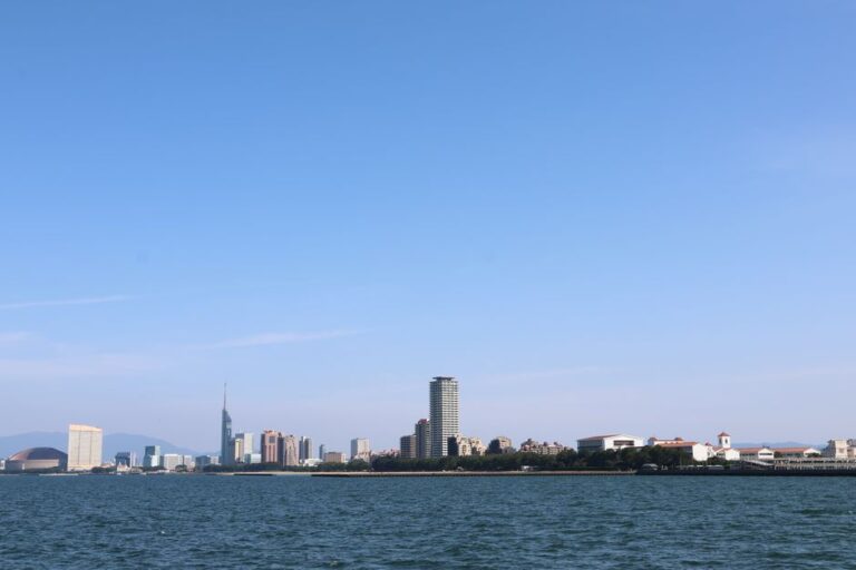 Panoramic skyline of Fukuoka City featuring iconic buildings along the waterfront under a clear blue sky.