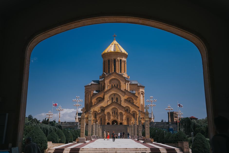 A stunning view of the Holy Trinity Cathedral framed by an archway in Tbilisi, Georgia.
