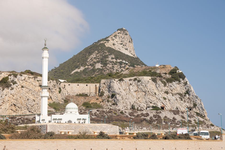 A scenic view of the Ibrahim-al-Ibrahim Mosque with the Rock of Gibraltar in the background.