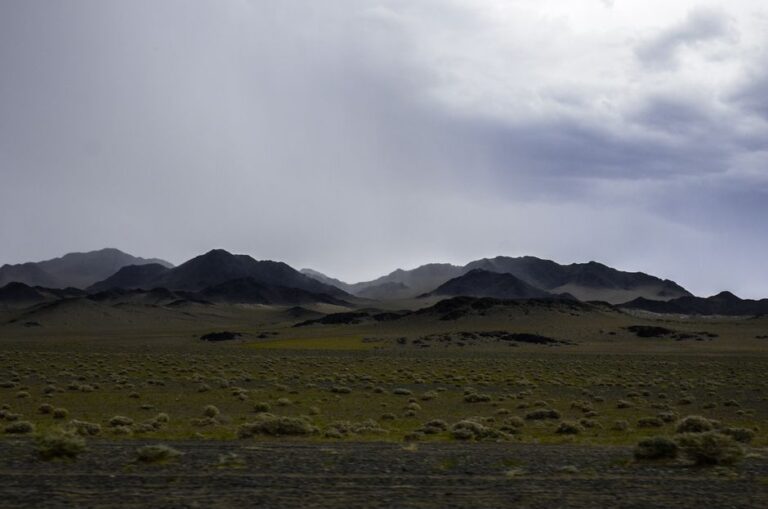 Scenic view of Mongolian mountains with cloudy sky, capturing the vast wilderness.