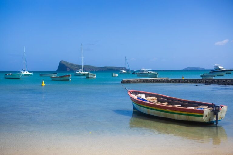 Colorful boats docked in pristine blue ocean with clear skies and distant islands.