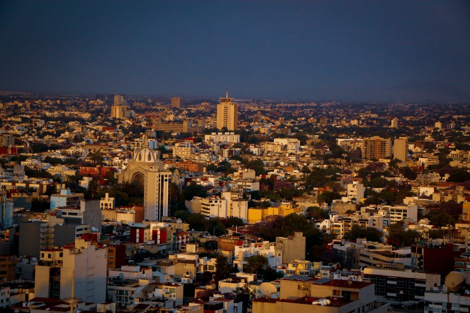 Aerial view of Guadalajara cityscape during sunset, showcasing vibrant buildings and warm colors.